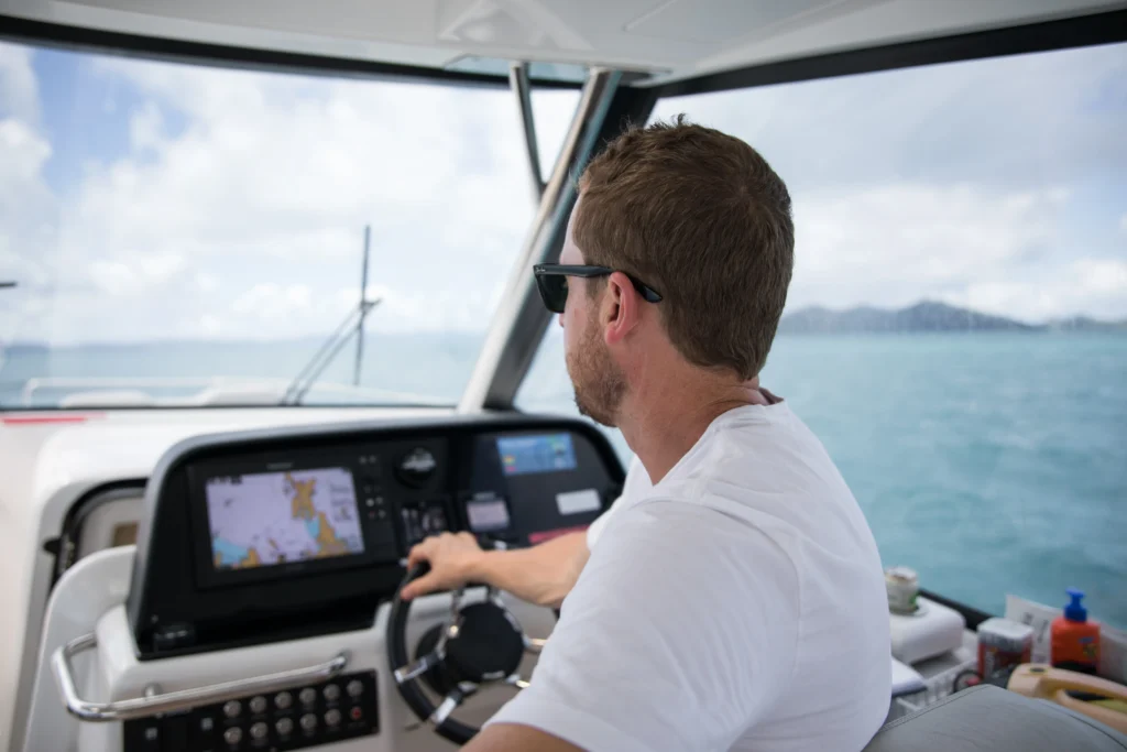 A man Piloting a boat with the help of GPS and Chartplotters